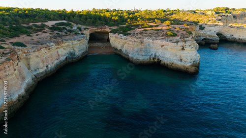Sand beach among rocks on evening sunset. Ursa Beach near Arcos Naturais da Praia da Marinha at Atlantic Ocean coast in Portugal. Summer landscape. 