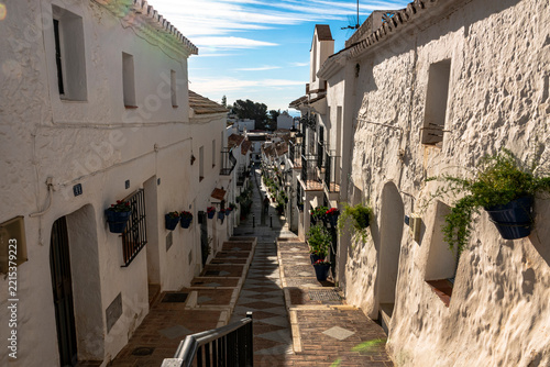 MIJAS, MÁLAGA, SPAIN – Traditional whitewashed street with flower pots and balconies in Mijas Pueblo, Spain.
