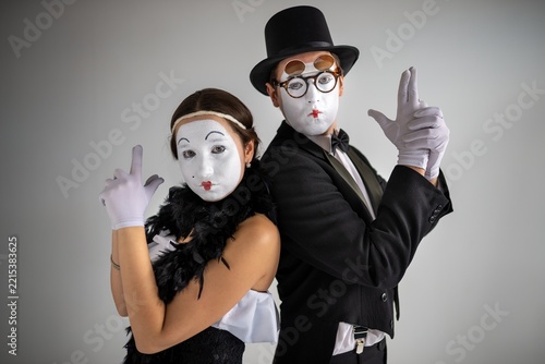 Mime couple standing back to back making hand gun signs