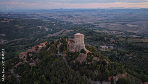 Aerial view of the historic Rocca di Tentennano fortress tower surrounded by lush green hills and the rolling landscape of Tuscany in Castiglione d'Orcia, Tuscany, Italy.