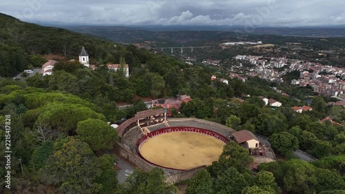View of an empty bullring in a town surrounded by buildings and trees during the day, Plaza de Toros de Bejar La Ancianita