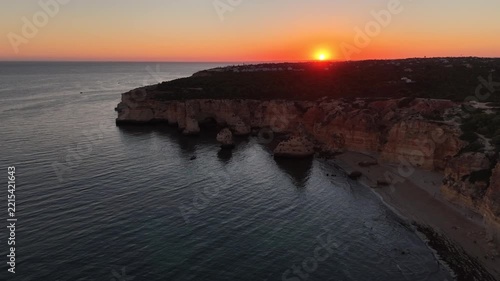 Sand beach among rocks on evening sunset. Ursa Beach near Arcos Naturais da Praia da Marinha at Atlantic Ocean coast in Portugal. Summer landscape. 