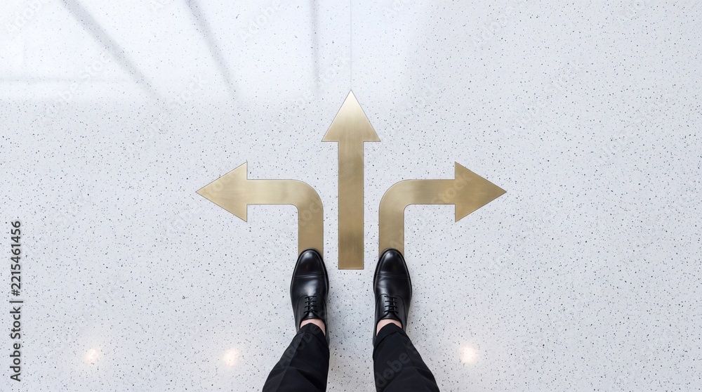 Fototapeta premium Businessman standing at a crossroads with three golden directional arrows on the floor, representing multiple choices, career paths, and strategic decision making in a premium office setting.