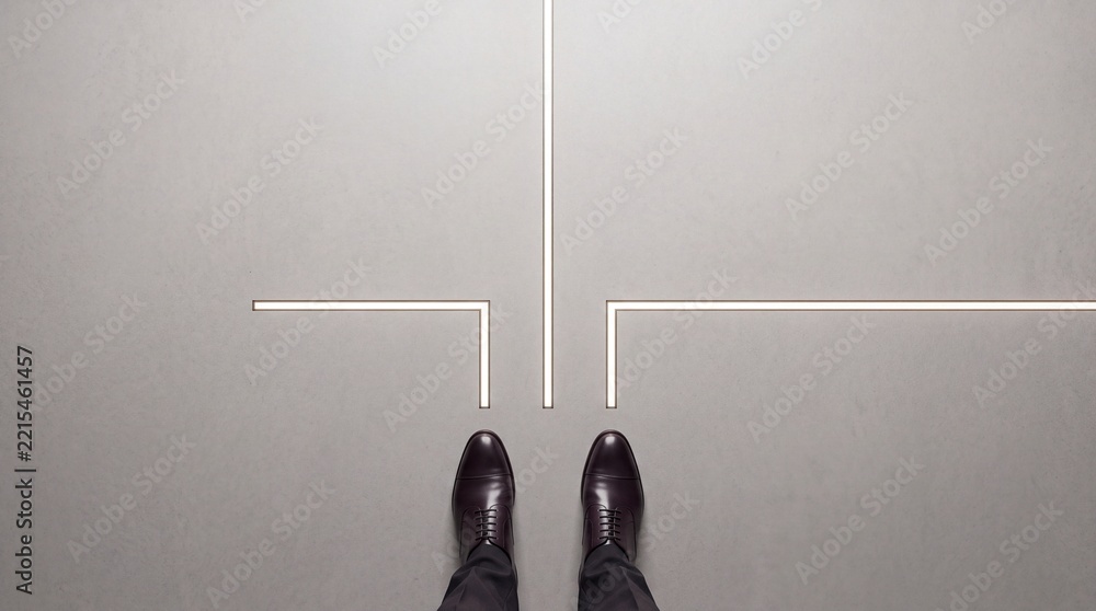 Fototapeta premium High Angle View of a Businessman Standing at a Luminous Crossroad on a Concrete Floor, Symbolizing Career Path Decisions, Strategic Business Choices, and Premium Commercial Growth Opportunities.