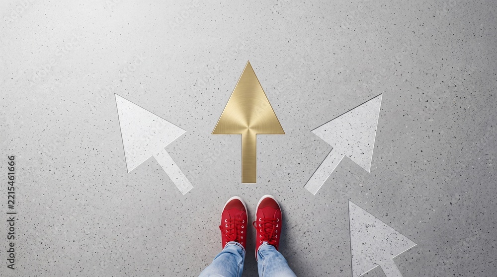 Fototapeta premium Person standing in red sneakers choosing a golden upward arrow path among grey direction symbols on a concrete background, representing premium commercial growth and successful decision making.
