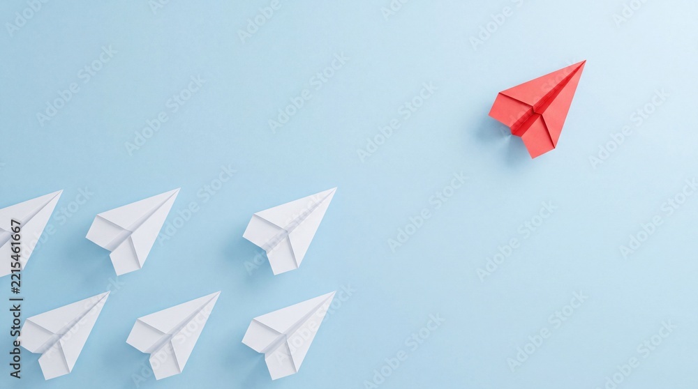 Fototapeta premium Top down overhead view of a single red paper plane flying in a different direction from a group of white paper planes on blue background representing leadership, innovation, and business vision.