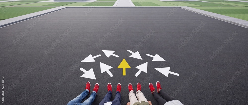 Fototapeta premium High Angle View of People in Red Shoes Sitting on Asphalt Road with Multiple Directional White Arrows and One Yellow Arrow Pointing Forward Symbolizing Decision Making, Leadership and Choice