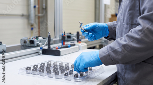 Factory worker inspecting metal components on an assembly line