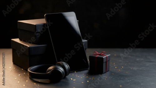Tablet with dark screen headphones and black gift boxes with confetti
