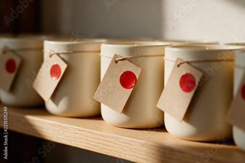 Cream ceramic candle jars with blank kraft tags and red sale stickers