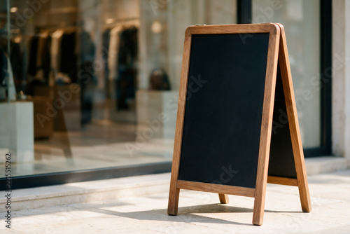 Blank wooden A-frame chalkboard sign in front of boutique storefront