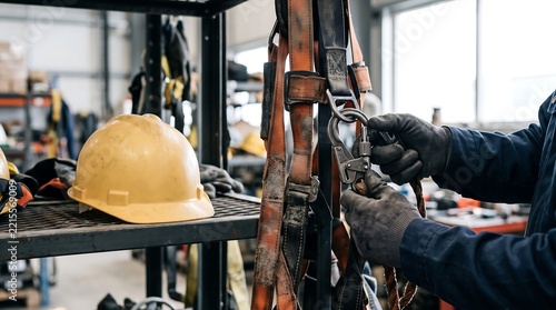 Worker checks safety harness and hard hat in industrial setting