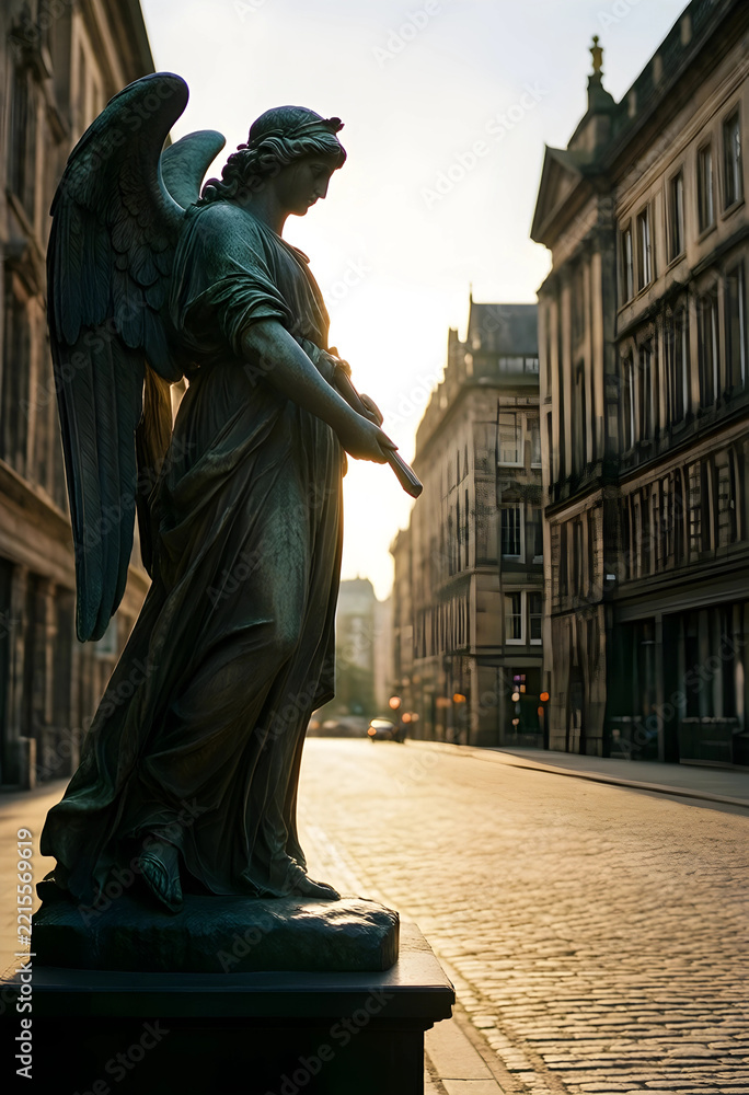 Fototapeta premium Spirituality and peace, bronze angel statue standing on a cobblestone street in a historic city center at sunset with warm golden hour light