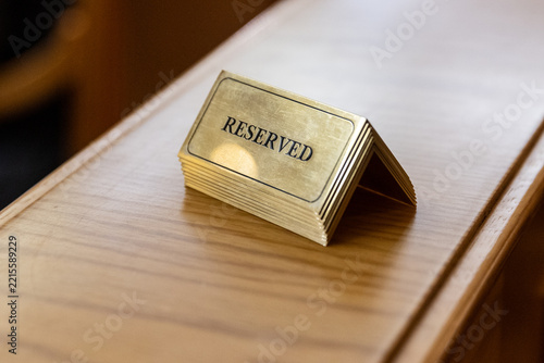Brass reserved sign on a polished wooden table in a restaurant close-up.