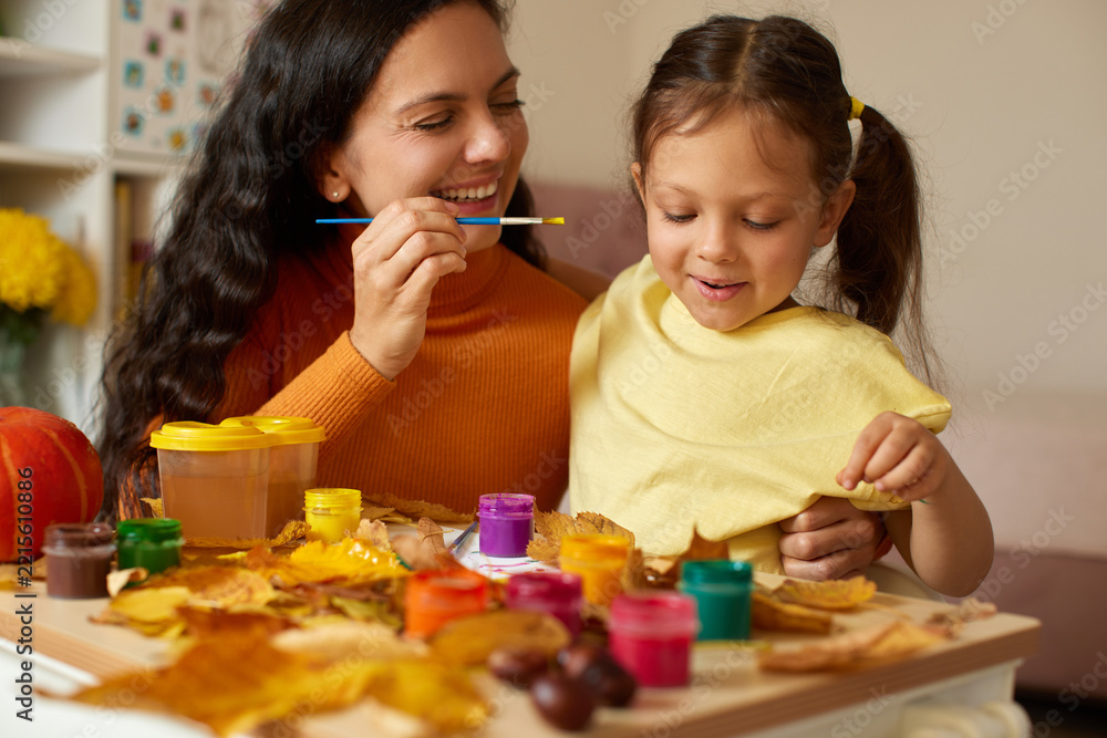 Fototapeta premium Mother and daughter painting autumn leaves creating art