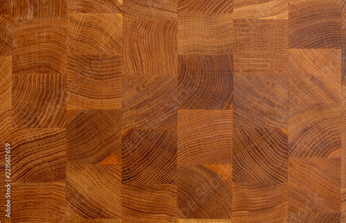 Full frame texture of a professional end grain wooden cutting board made of oak blocks. Detailed close-up background of butcher block butcher board texture with checkered pattern
