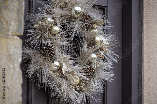 Christmas wreath with silver glitter foliage gold baubles pinecones and berries on a dark door holiday decoration