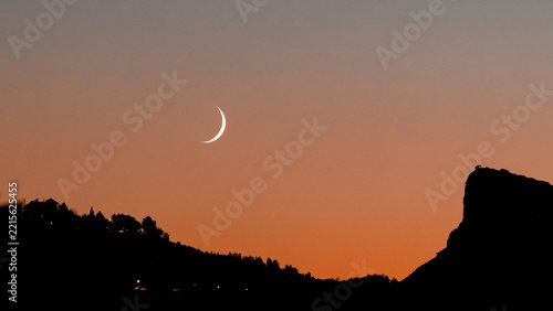 Crescent Moon in Twilight Sky Over Silhouette Landscape