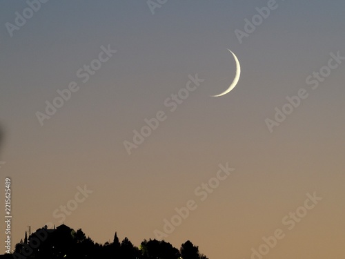 Crescent Moon Above Silhouetted Hilltop Village at Night