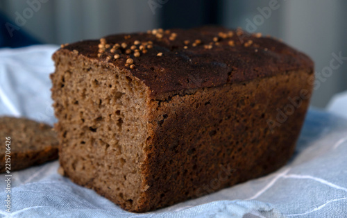 Traditional Borodinsky sourdough rye bread loaf with coriander seeds and a cut slice on a linen napkin.