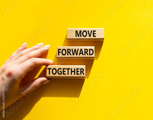 Concept words move forward together on wooden blocks arranged as steps. Businessman hand arranging wooden blocks. Teamwork and collaboration concept. Yellow background. Copy space.