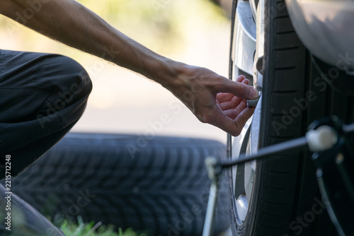 Hand loosening wheel nut on car tire during tire change