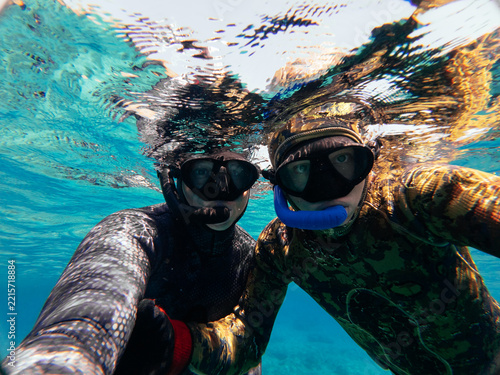 father and son taking selfie in clear mediterranean water
