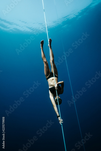 female freediver descending headfirst on a training line