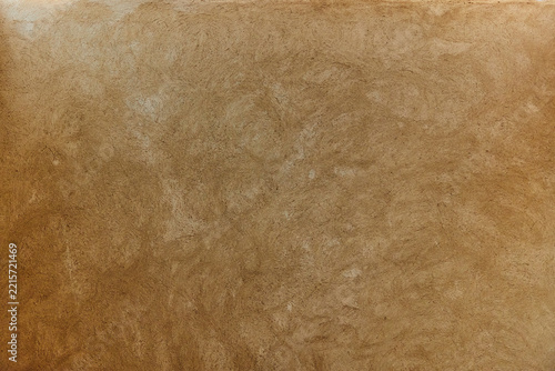 Warm brown earthen wall with textured plaster and circular trowel marks