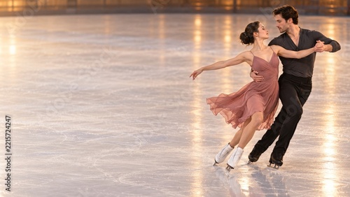 Elegant Figure Skating Couple Turning Together on a Warmly Lit Ice Rink