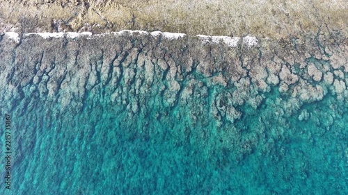 Calm seas wash against the beautiful coastline of the remote Maju Island in the Molucca Sea, Indonesia. A rugged, rocky reef surrounds this tropical paradise which few people ever visit.