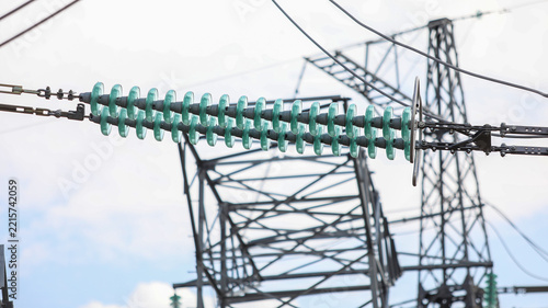 Glass insulators separating high voltage power lines on an electricity pylon, symbolizing energy transmission, infrastructure, and the distribution network