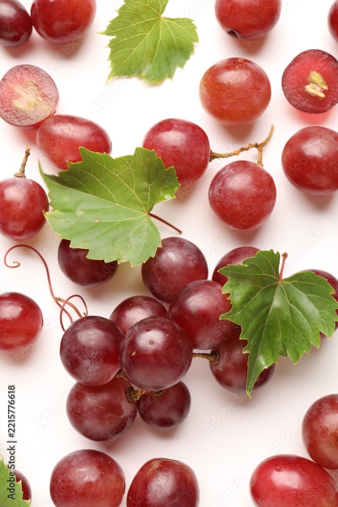 Naklejka premium Fresh ripe grapes and green leaves on white background, flat lay