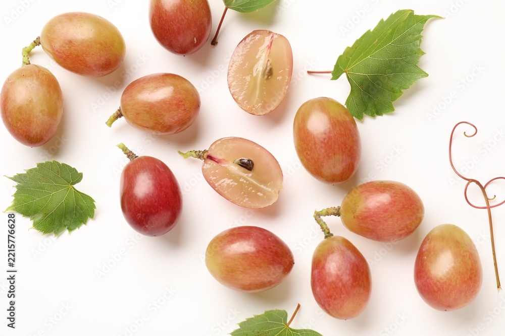 Naklejka premium Fresh ripe grapes and green leaves on white background, flat lay