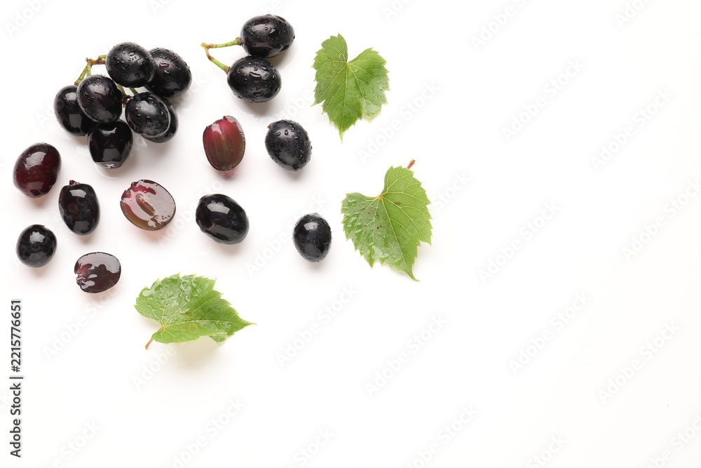 Naklejka premium Fresh ripe grapes and green leaves on white background, flat lay. Space for text