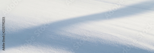 Soft, undisturbed snow with gentle shadows creating a serene winter scene.