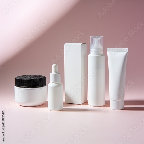 White cosmetic containers and skincare bottles mockup on pink background