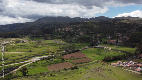 Aerial view of the ancient Incan ruins of Sacsayhuaman with terraced fields, green hills, and rural settlements in Cusco, Cusco, Peru.