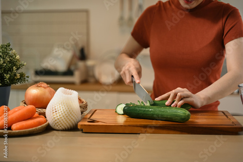 Cropped of Young Asian Woman Preparing Fresh Salad by Cutting Cucumber on Wooden Board in Modern Kitchen