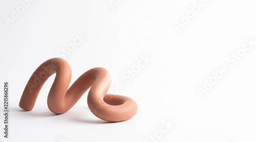 Smooth, curved, tan-colored clay form on a white background