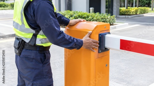 Security officer operating a barrier gate at an entrance with access control security guard parking lot building security