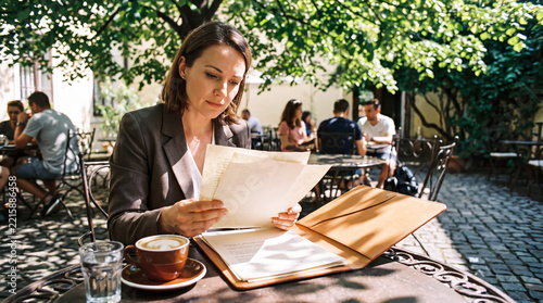 Professional woman reviewing resume at outdoor cafe table