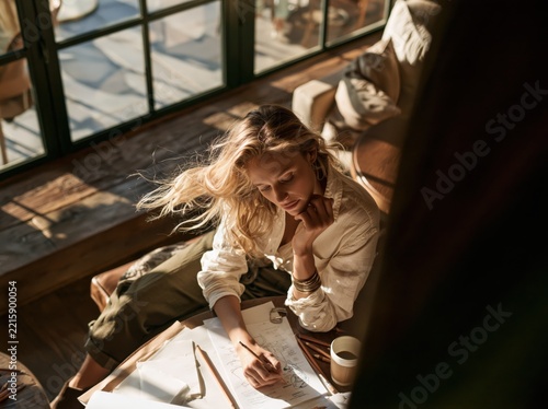 Woman drawing at a table with sunlight streaming in