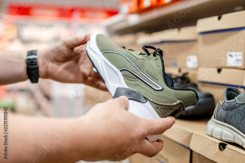 Person holding olive green Puma sneaker