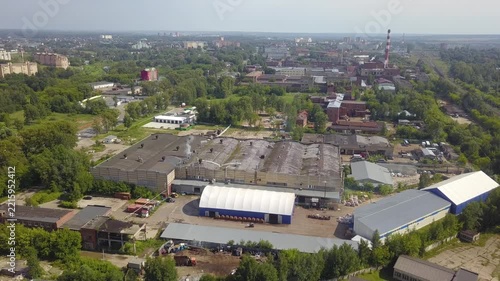 Drone rises backward over a Klin warehouse yard