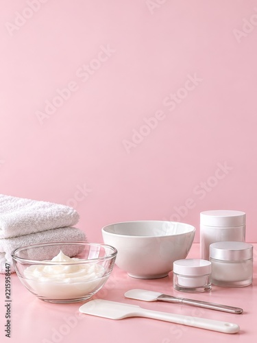 Facial treatment bowls and skincare jars on a soft pink backdrop