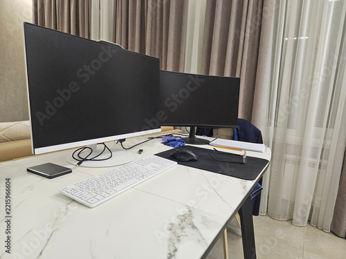 Modern desk holds two monitors, keyboard, and mouse. White marble surface reflects soft room lighting. Curtains frame the background, adding subtle depth. Setup suggests a clean, organized workspace