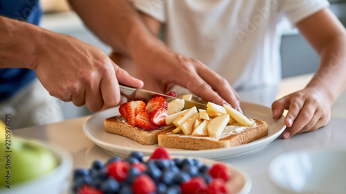 Hands-only scene of parents preparing a child's breakfast, cutting fruit and spreading toast on a plate, healthy childhood nutrition, parenting, family care, wholesome food,