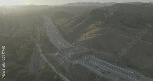 Aerial view of highway lanes passing under bridge among dry hills