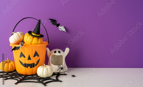 Happy Halloween decorations with jack-o-lantern bucket, ghost and pumpkin display on purple background